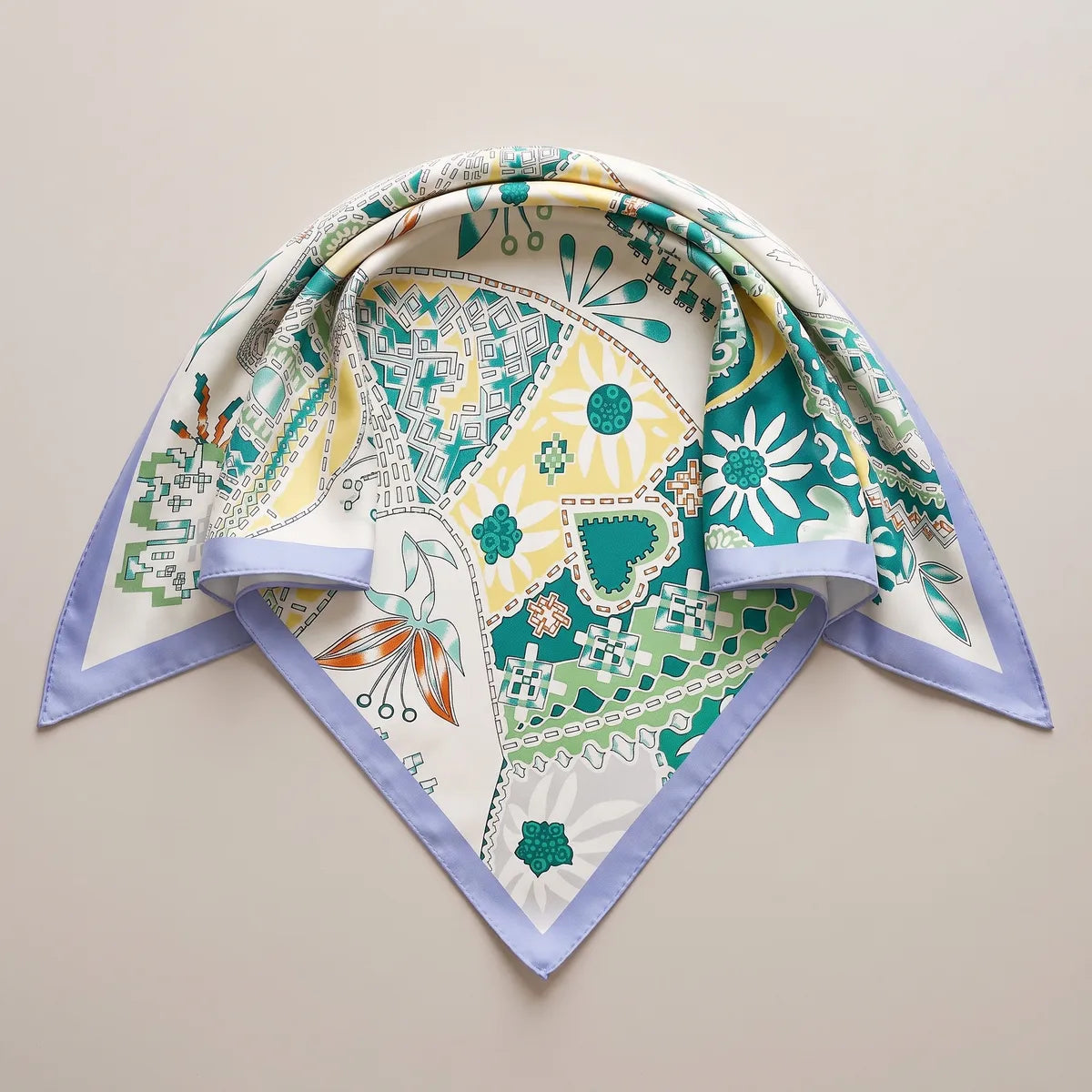 White and teal folk print shawl folded into a triangle, a teal heart at the center and a pale daisy at the point