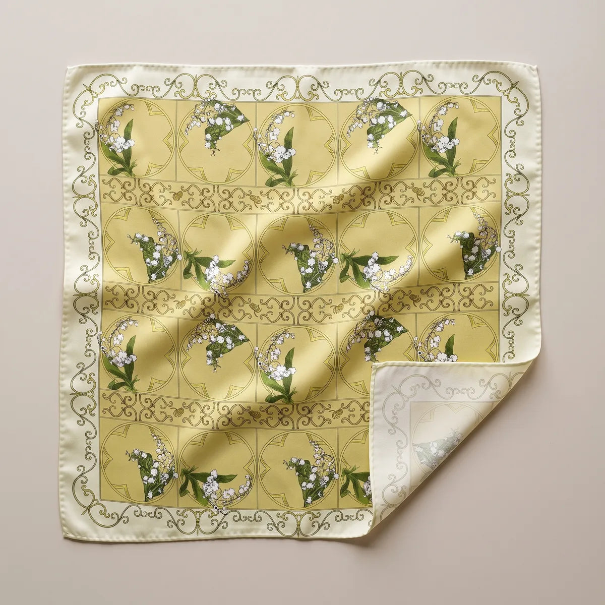 Yellow lily of the valley silk square scarf laid flat: white bell flowers in a tiled grid, cream scroll border