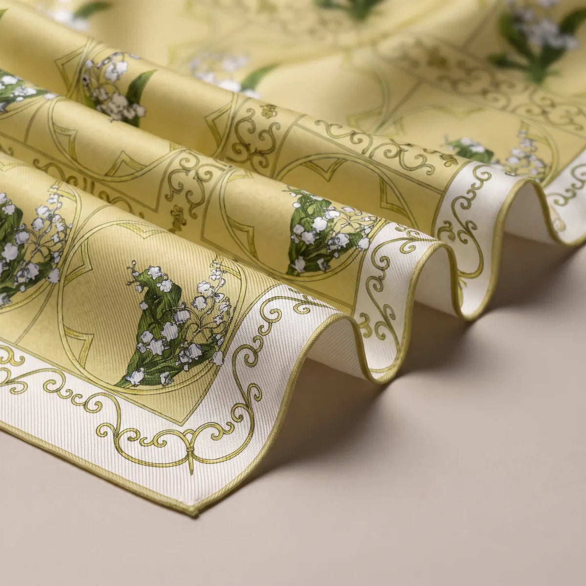 Folds of the yellow lily scarf showing olive scrollwork, the cream border and its fine stitched edge