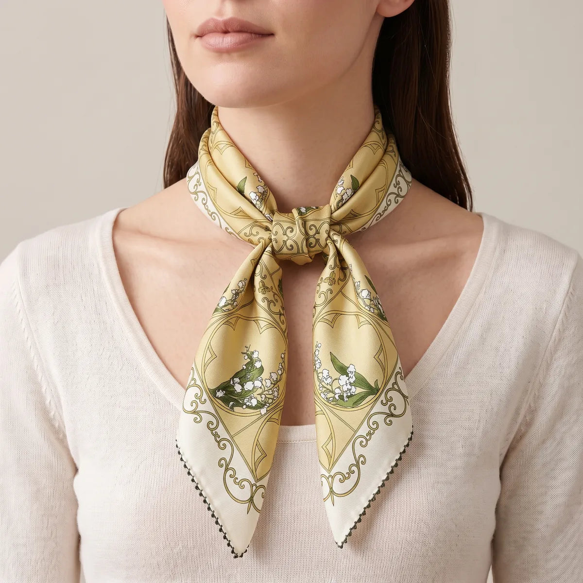 Butter yellow lily scarf in a front neck knot, cream-bordered tips falling over a V-neck sweater